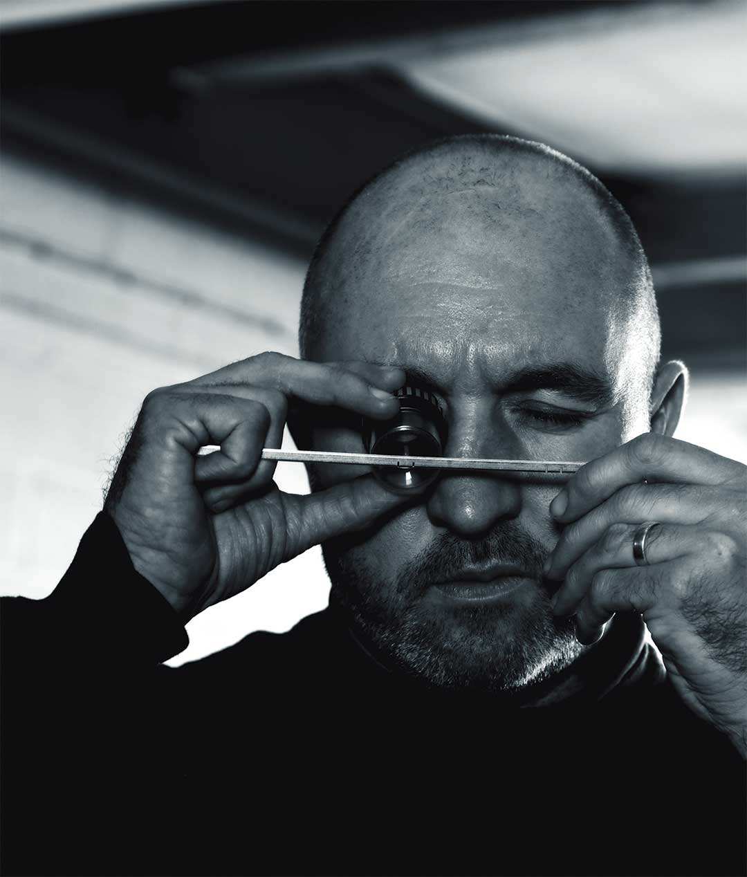 A craftsman checking a tungsten dart through a loupe