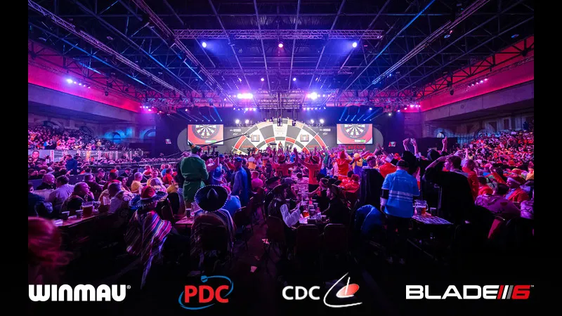 A full arena at a PDC event, branded with Winmau, the PDC, the CDC and Blade 6